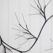 Black branch wall decor with multiple thin branches and small metallic bead accents, mounted against a white paneled wall.