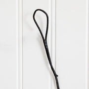 A single black leather or faux-leather loop hook hanging against a white paneled wall.