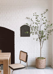 Dining area with a white brick wall, wooden table, chair, and potted plant.