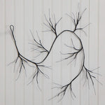 Black wire wall art shaped like a branching tree or abstract root system, mounted against a white paneled wall.