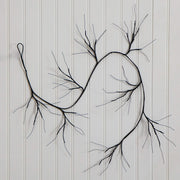 Black wire wall art shaped like a branching tree or abstract root system, mounted against a white paneled wall.