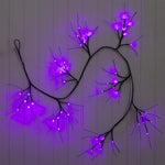 Decorative wall art with black branches and purple LED lights on a gray background