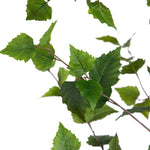 Green artificial birch leaves on a brown faux branch, isolated on a white background.