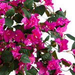 Vibrant artificial bougainvillea flowers in bright magenta pink with dark green leaves, shown against a solid white background.