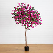 An artificial bougainvillea tree with bright pink flowers and green leaves, mounted on a brown trunk in a black pot, set against a white paneled wall and light wood floor.