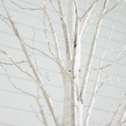 White birch tree artificial branch decoration with thin silver wire lights and small warm yellow bulbs, shown against a light gray background.