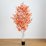 Artificial potted tree with orange leaves on a wooden floor against a white wall