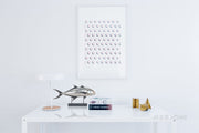 Decorative wall art with circular patterns on a white wall, featuring a fish sculpture and books on a table.