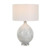 Table lamp with textured ceramic base and white fabric shade on a white background