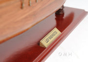 Wooden model ship with a gold nameplate on a white background