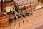 Close-up of a wooden model ship with rigging details, featuring the brand 'OMH'.