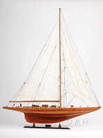Wooden model sailboat with white sails on a plain background
