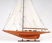 Wooden model sailboat with white sails on a white background