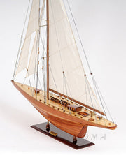Wooden model sailboat with white sails on a white background
