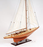 Wooden model sailboat with white sails on a gray background