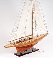 Wooden model sailboat with white sails on a gray background