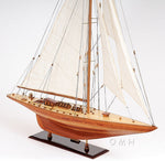 Wooden model sailboat with white sails on a white background