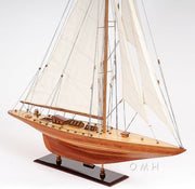 Wooden model sailboat with white sails on a white background