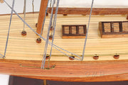 Close-up of a wooden model ship with ropes and a visible brand name.